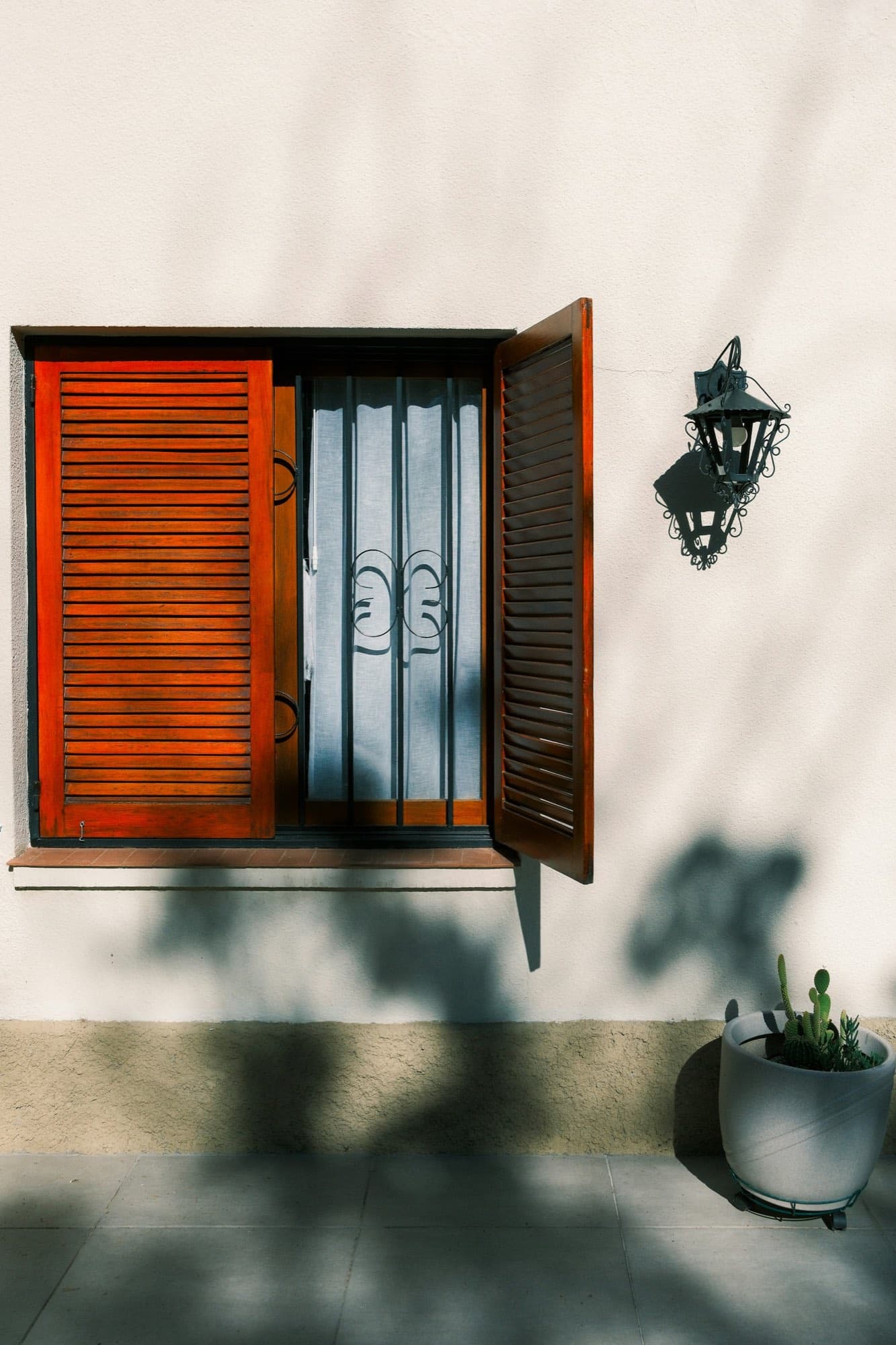 An orange shutter set against a painted teal window