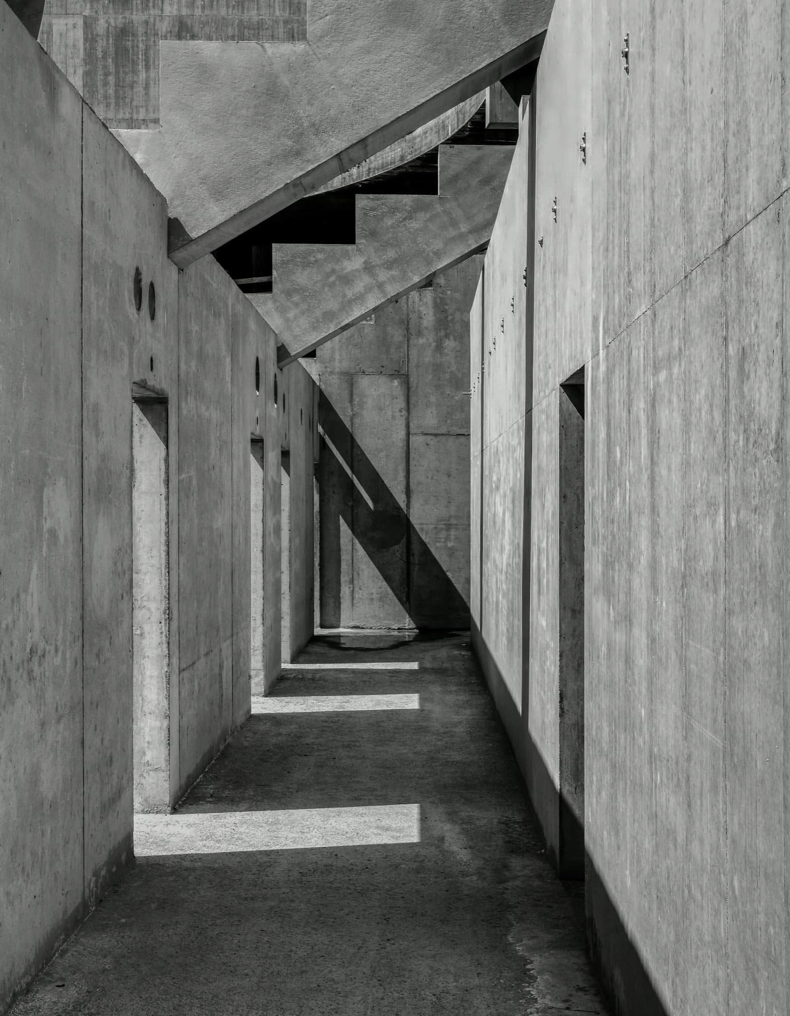 A raw concrete corridor with strong vertical shadows