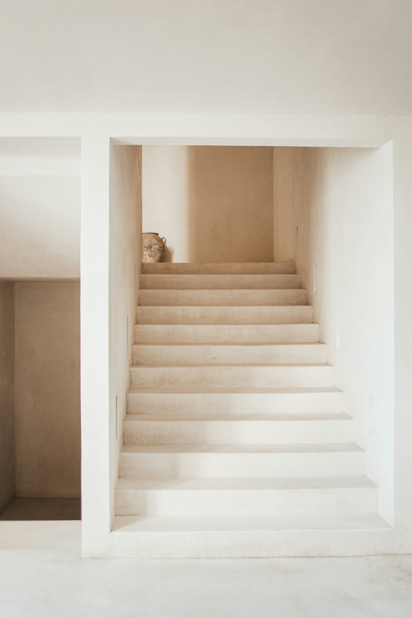 A pale stone staircase rising into warm, diffuse light