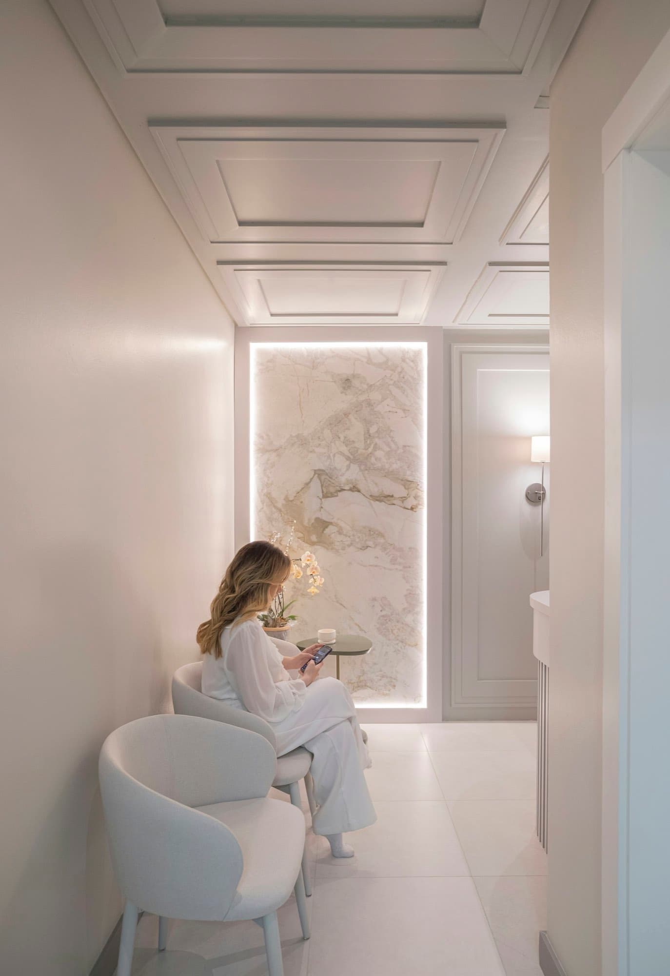 A figure standing in a corridor lit through backlit marble